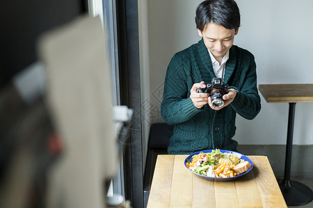 男子在咖啡馆里对食物拍照图片