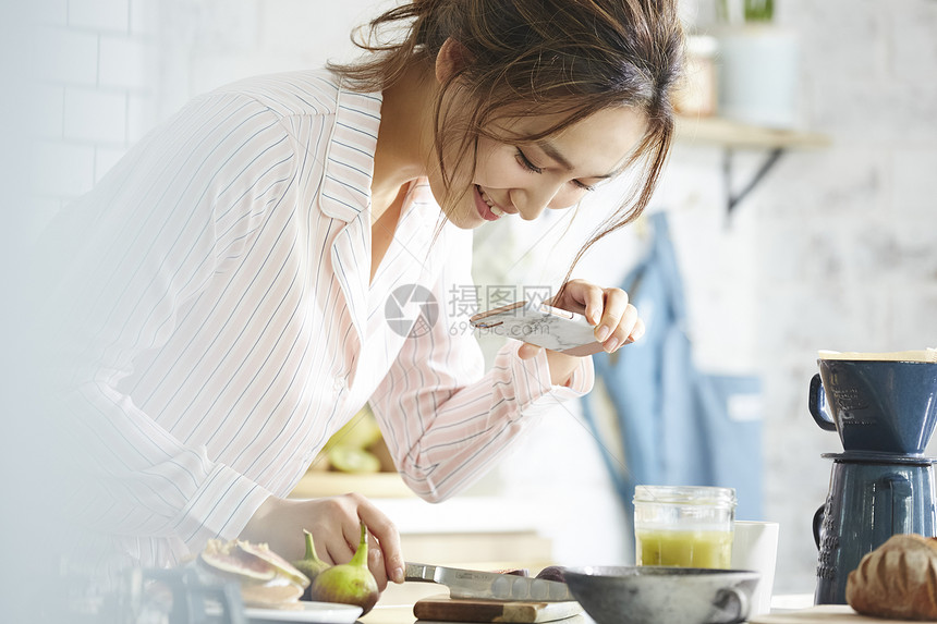 用手机拍摄自制早餐的职业女性图片