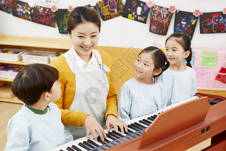 幼儿园老师教小朋友弹钢琴店员高清图片素材