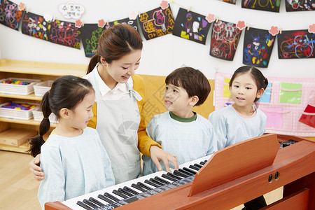 幼儿园女老师给小朋友弹钢琴微笑高清图片素材