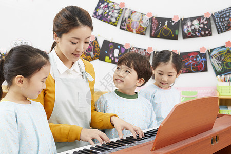幼儿园女老师给小朋友弹钢琴门厅高清图片素材