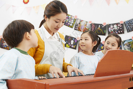 幼儿园女老师给小朋友弹钢琴男孩高清图片素材