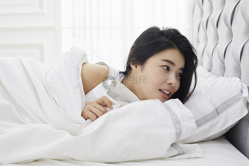 躺在床上休息的年轻女子图片