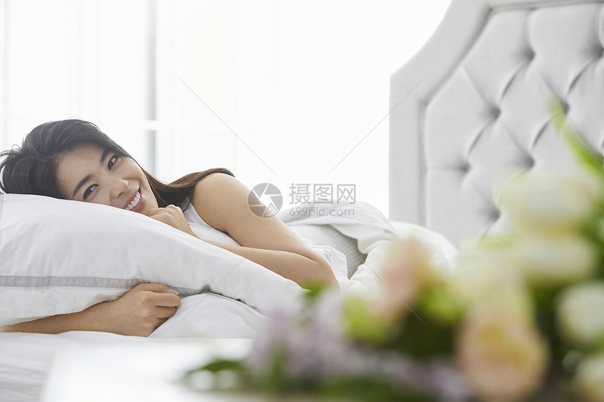 床上抱着枕头微笑的青年女子图片