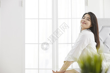 坐在床上微笑的年轻女子韩国人高清图片素材