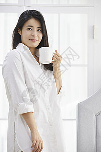 拿着水杯微笑的年轻女子咖啡高清图片素材