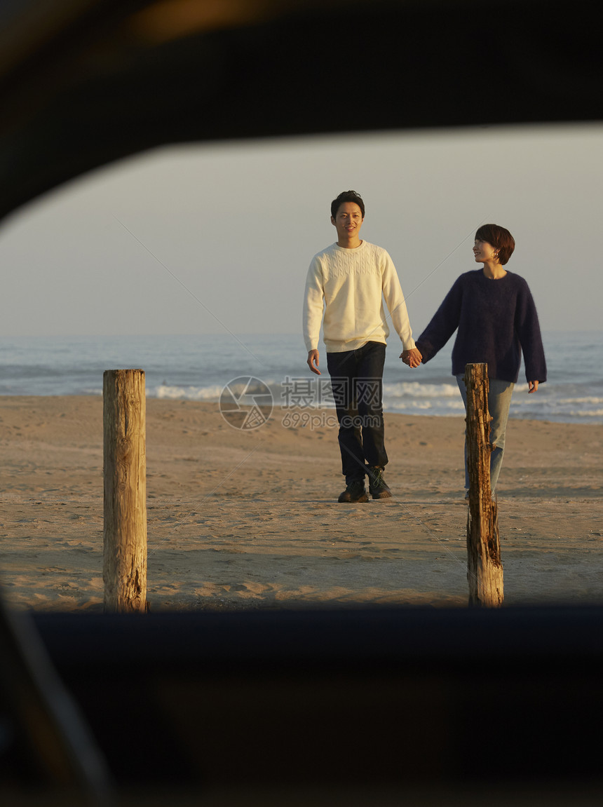 三十几岁演奏亲密一对夫妇沿着海岸散步图片