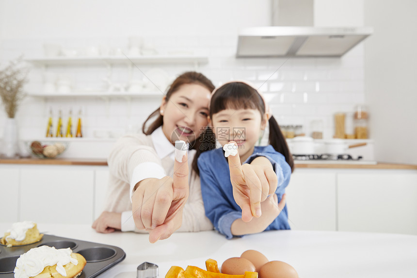 厨房里食指沾上奶油的母女图片