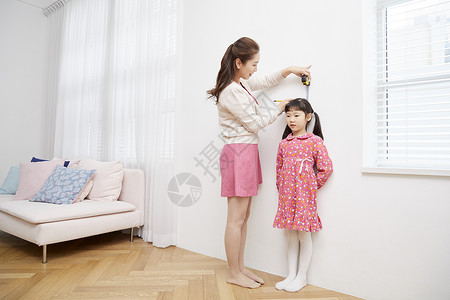拿着卷尺在墙上测量身高的小女孩图片