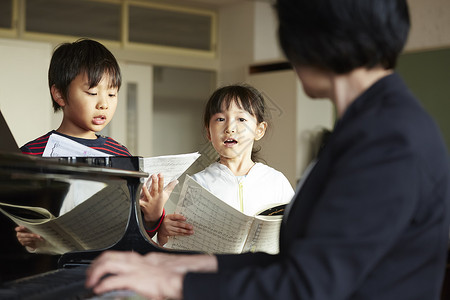 演奏钢琴男生小学生音乐室的老师和学生背景