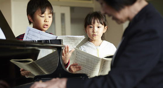 演奏钢琴男生音乐室的老师教学生背景