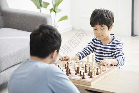 客厅里下棋拿起象棋的小男孩图片