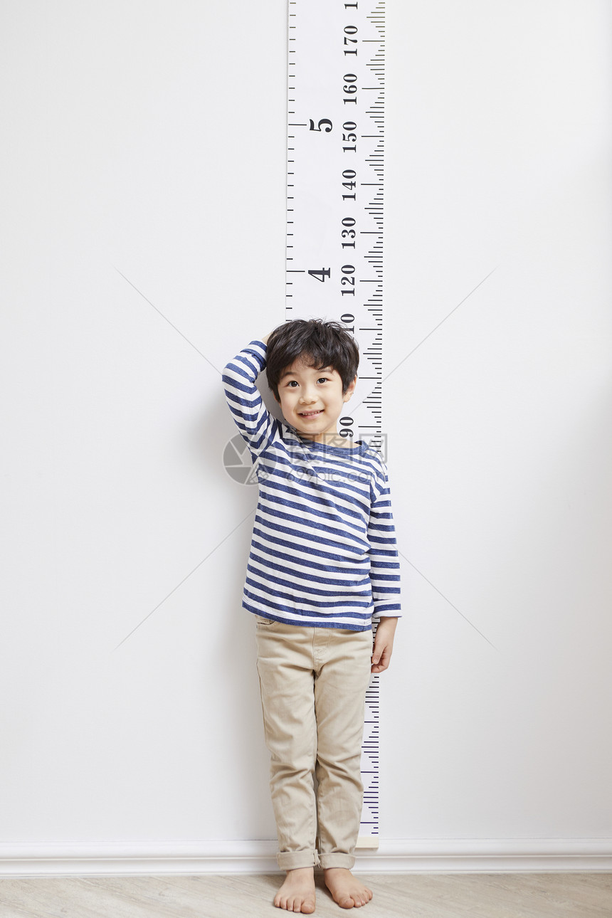 靠在墙上测量身高的小男孩图片
