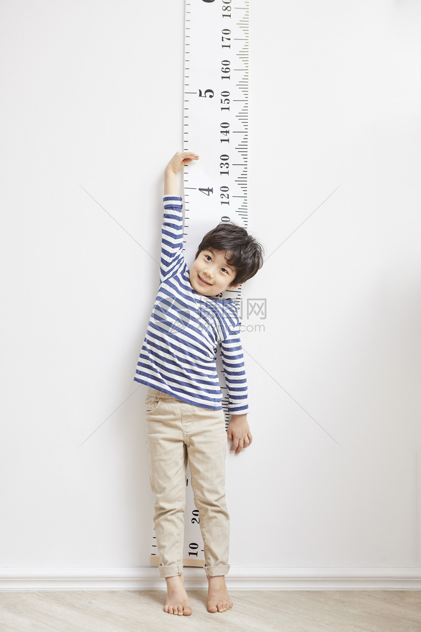 踮脚测量身高的小男孩图片