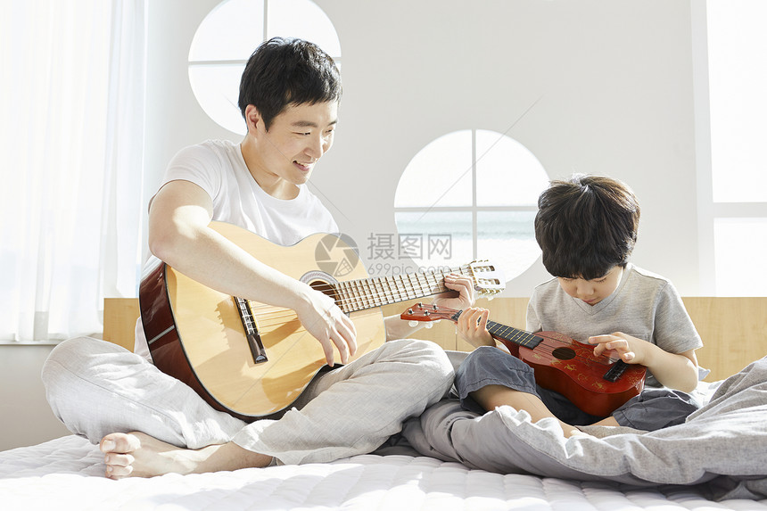 床上拿着吉他的父子俩图片