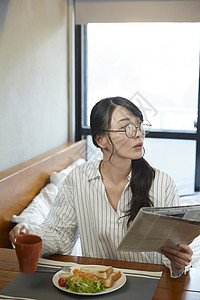 早餐拿着报纸的青年女子图片