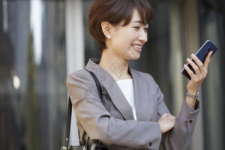 公司外面女商人用智能手机背景图片