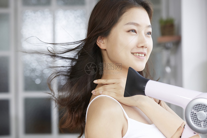 年轻女性吹风机护发图片