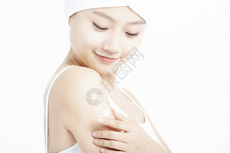 女青年低头涂抹手臂的乳液图片