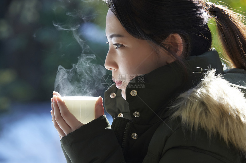 年轻女孩秋冬保暖捧着热茶图片