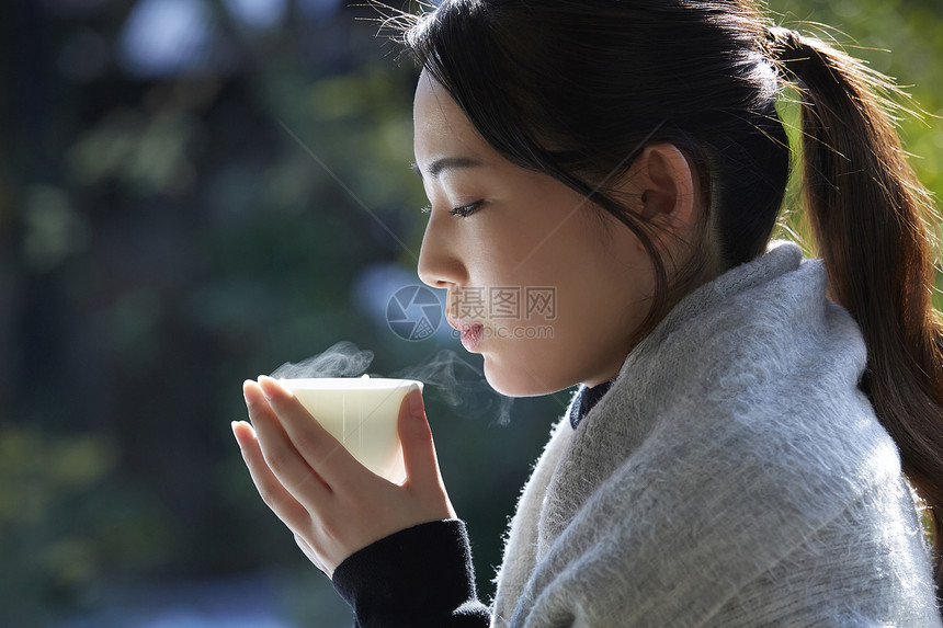 年轻女孩秋冬保暖捧着热茶图片