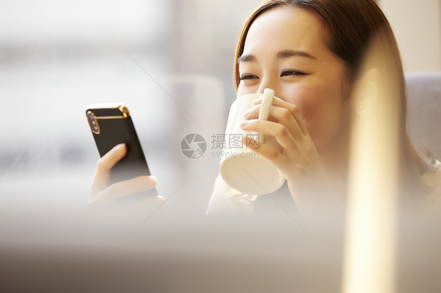喝咖啡看着手机的女青年图片