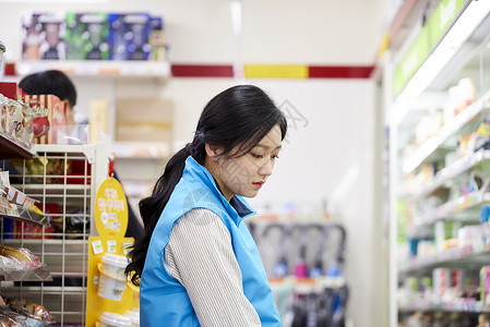 便利店兼职陈列商品的年轻女子图片