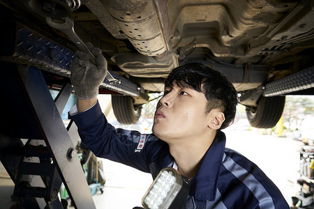 修理工在检修汽车排气管高清图片素材