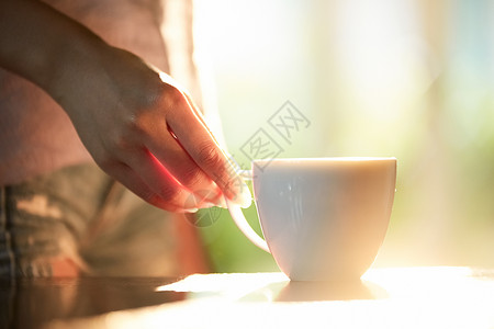 夕阳下拿咖啡杯的特写图片