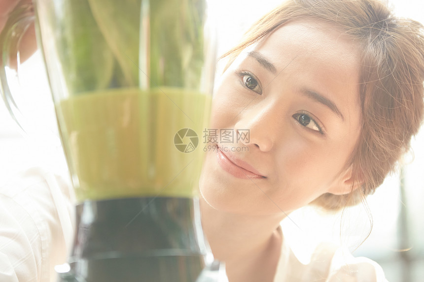 看着蔬菜榨汁机微笑的少女图片