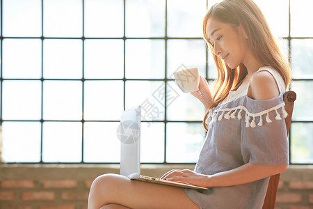 居家喝下午茶看电脑的年轻女子图片