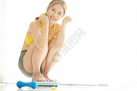 测量体重开心的年轻女子图片