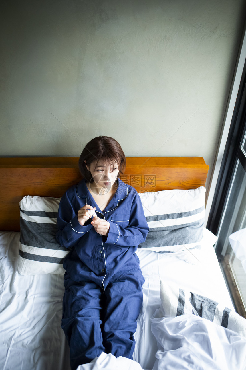 卧室床上涂指甲油的年轻女孩图片