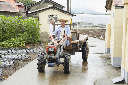 驾乘险老年夫妇驾乘拖拉机下农田背景