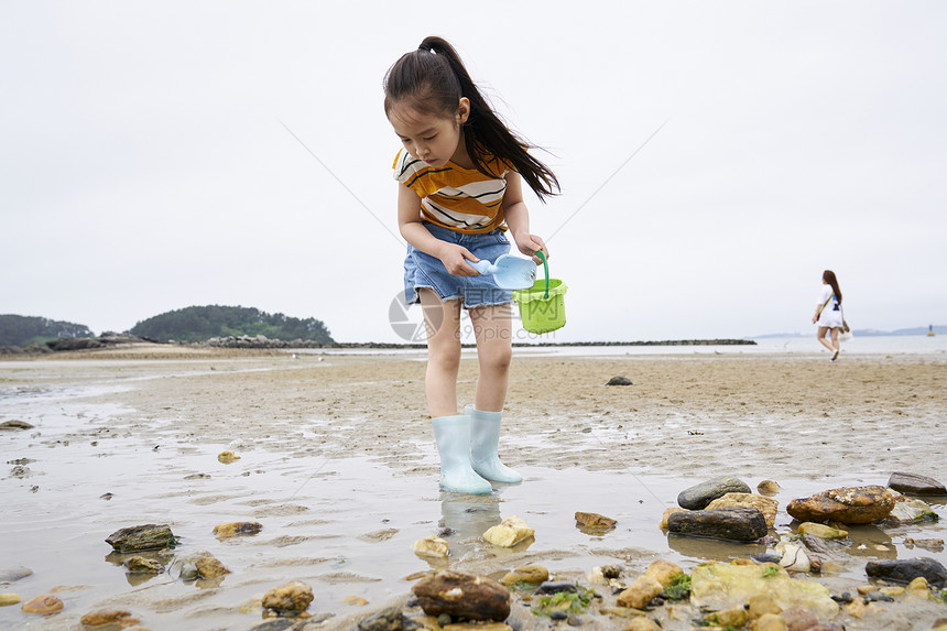 在海边捡石子的小孩