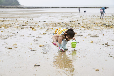 在海边捡石子的小孩长靴高清图片素材