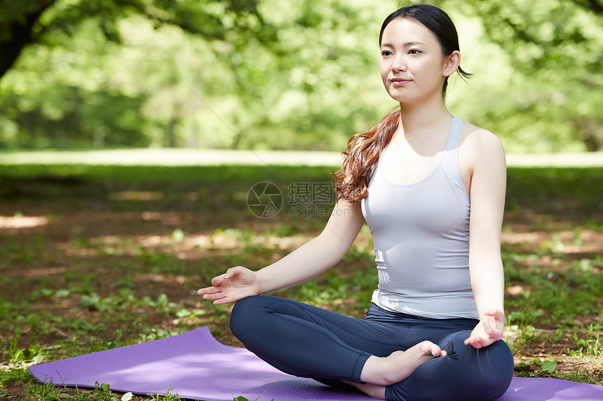 瑜伽垫上盘腿坐冥想的青年女性图片