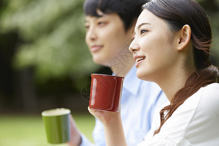 公园里拿着野餐拿着水杯的情侣图片