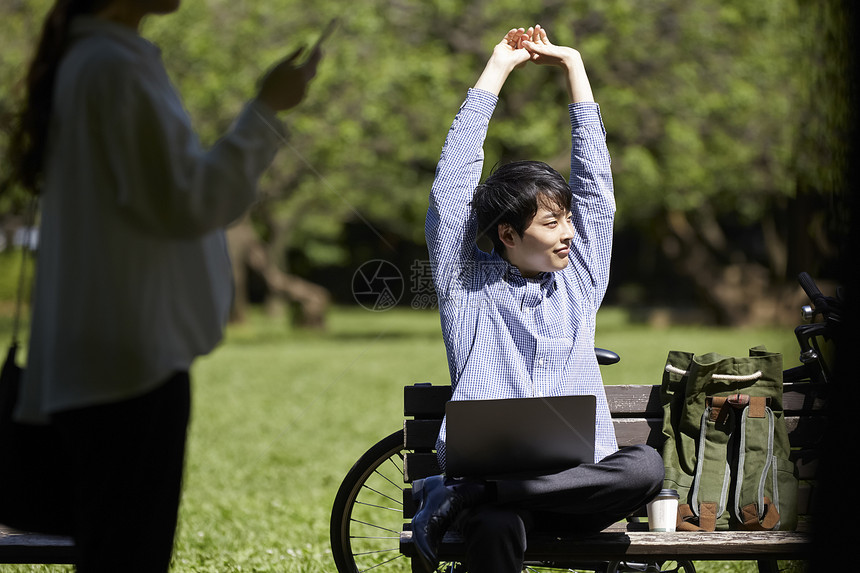 长凳上拉伸双臂的男青年图片