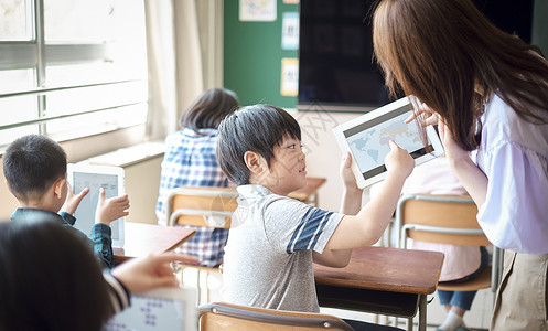 小学生在老师的指导下学习平板电脑使用知识教育高清图片素材