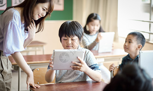 小学生在老师的指导下学习平板电脑使用知识快乐高清图片素材