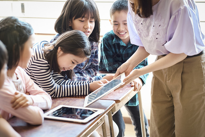 小学生在老师的指导下学习平板电脑使用知识图片