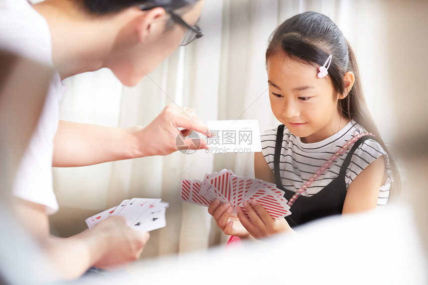 室内爸爸陪女儿愉快玩纸牌图片