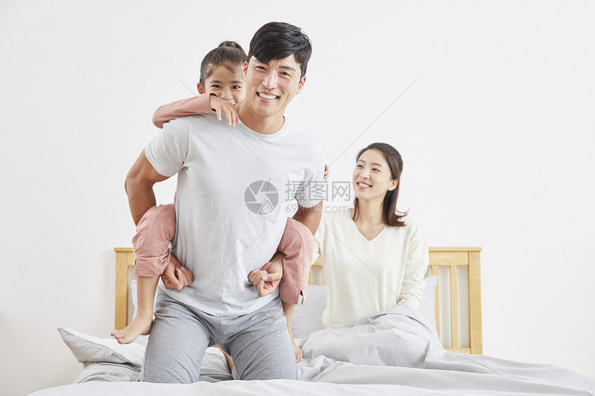 幸福的一家三口在床上玩耍图片