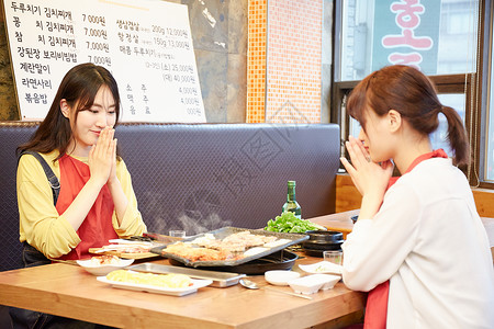 韩式烤肉店年轻女人们在餐厅吃烧烤背景