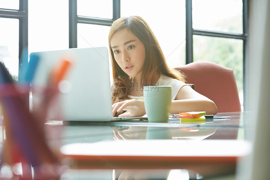 使用便携电脑女商人在书桌上工作图片