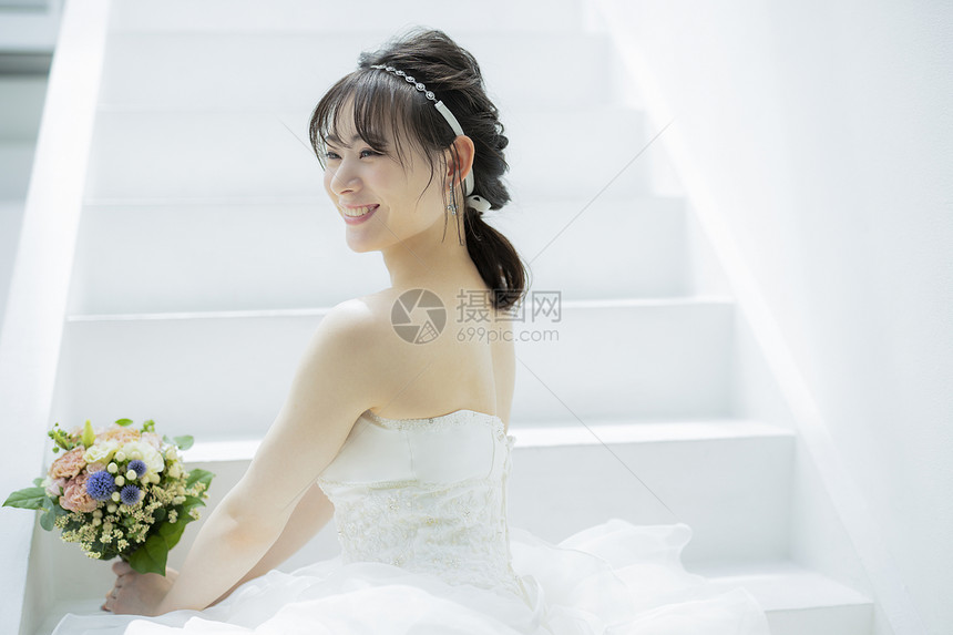 坐在台阶上微笑开心的婚纱美女图片