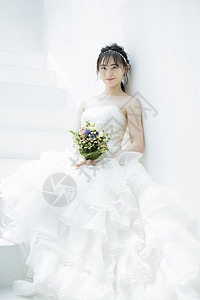 坐在台阶上拿着手捧花微笑的新娘图片