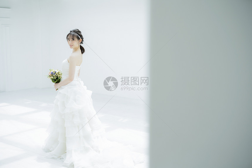 年轻女子穿着纯白的婚纱拿着手捧花图片