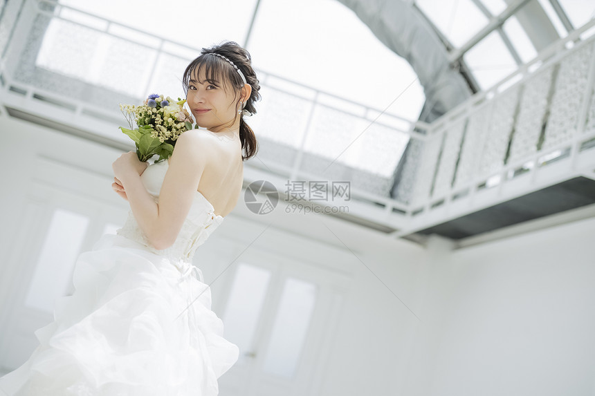 新娘穿着纯白的婚纱拿着手捧花图片